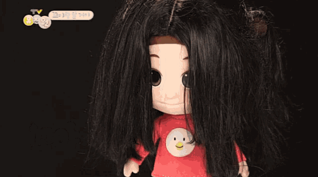 a doll with long black hair is wearing a red shirt with a bird on it ..