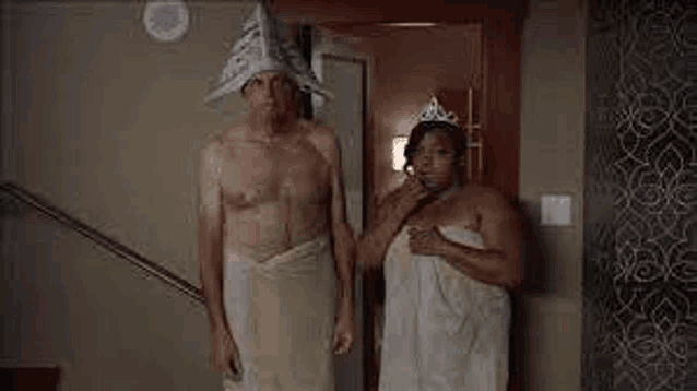 a man and a woman wrapped in towels are standing next to each other .