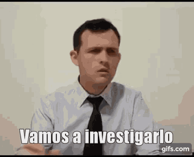 a man in a shirt and tie is sitting at a desk and talking .