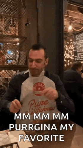 a man is sitting at a table with a bag of food and says " mm mm mm purrgina my favorite " .
