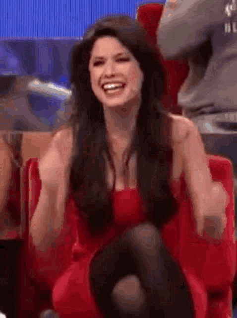 a woman in a red dress is sitting in a chair laughing .