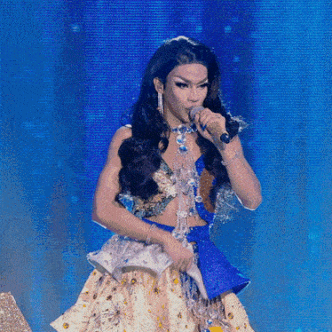 a drag queen sings into a microphone on stage