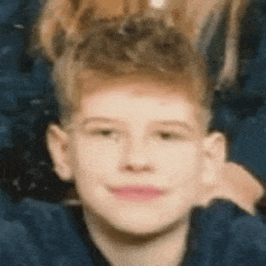 a close up of a young boy 's face with a very messy haircut .