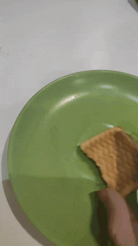 a green plate with a cracker on it on a table