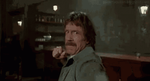 a man with a mustache is making a funny face while throwing a fist in the air .