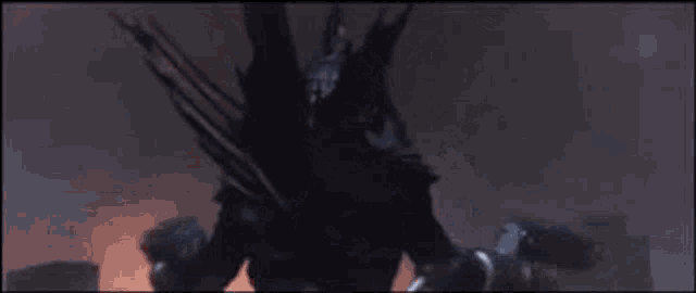a monster with wings and spikes is flying through the air in a dark room .