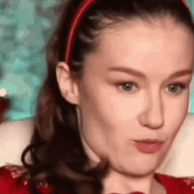 a close up of a woman wearing a red headband and making a funny face .