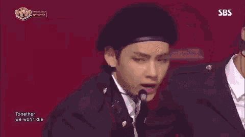 a man wearing a beret and a suit is singing into a microphone .