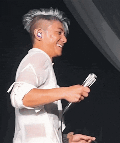 a man in a white shirt is holding a microphone