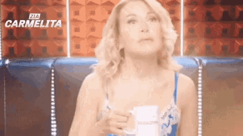 a woman is holding a cup of coffee in front of a carmelita sign