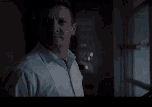 a man in a white shirt stands in front of a window with the words " this is some christmas " above him