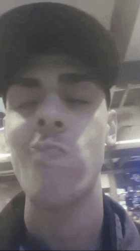 a man wearing a baseball cap is making a funny face with his eyes closed .