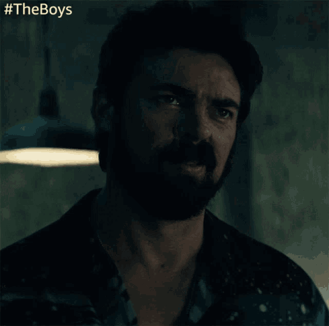 a man with a beard is smiling in a dark room with #theboys written in the corner