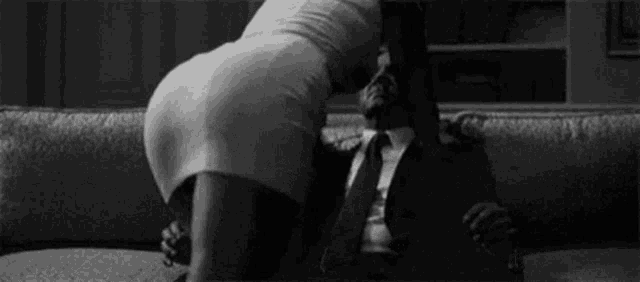 a man in a suit and tie is sitting on a couch with a woman in a dress .