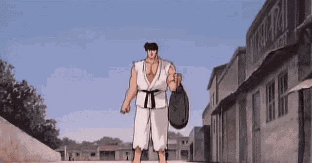 a man in a karate uniform is walking down a street holding a bag ..