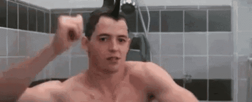 a shirtless man is taking a shower in a bathroom and brushing his hair .