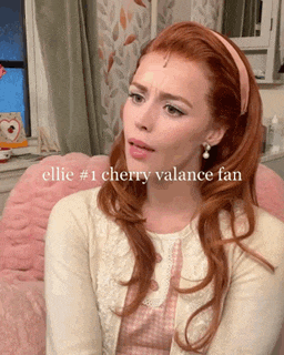 a woman with red hair is sitting in a chair with the words ellie # 1 cherry valance fan written below her