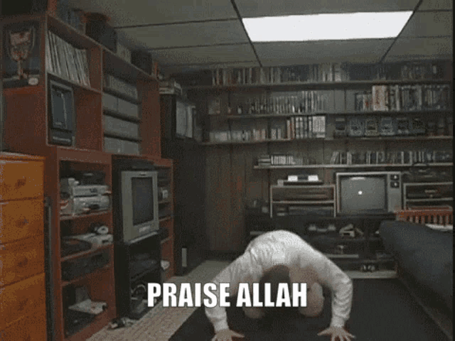 a man is kneeling down in a living room with his arms in the air and the words praise allah behind him