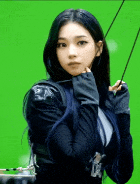 a woman with blue hair is holding a bow and arrow on a green screen