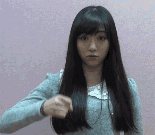 a woman with long black hair is pointing at something