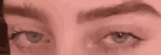 a close up of a woman 's blue eyes with a pink background .