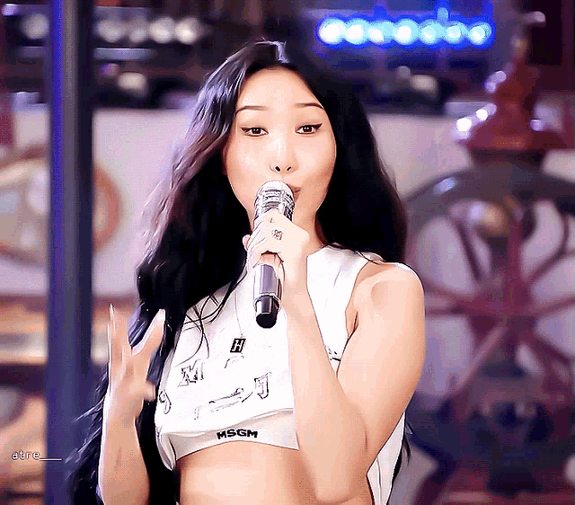 a woman singing into a microphone wearing a crop top with msgm on it