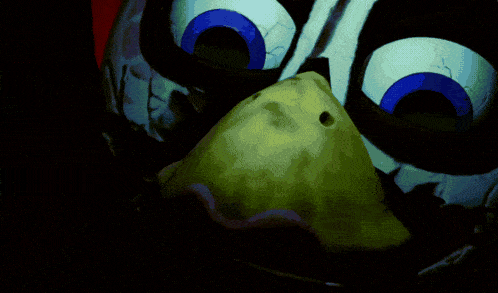 a close up of a cartoon character 's face with a green object in its mouth