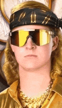 a man wearing sunglasses and a headband with a gold chain around his neck