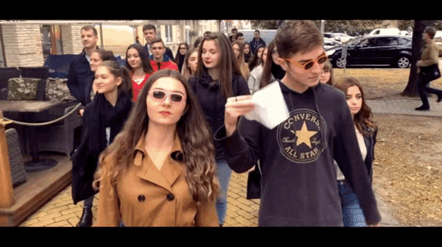 a man wearing a black converse all star shirt walks with a woman