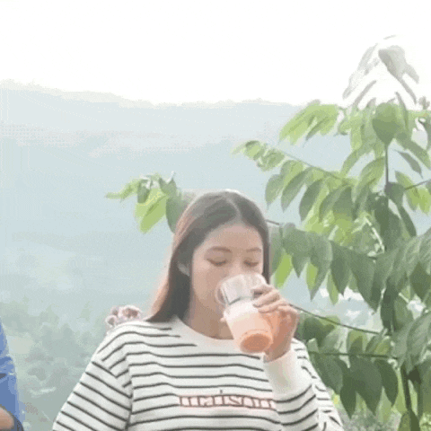a woman wearing a striped shirt is drinking from a cup .