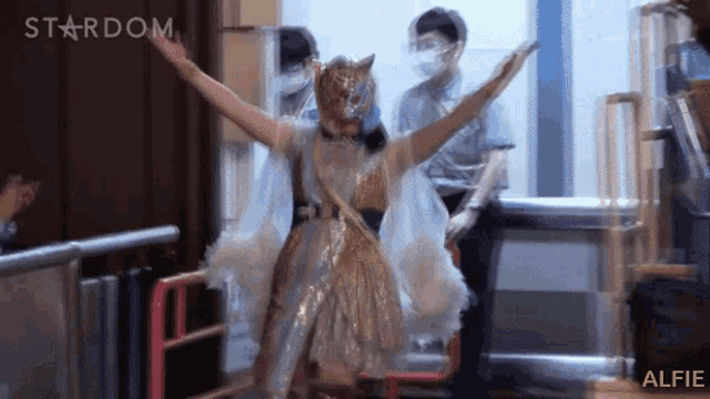 a woman wearing a mask and a white dress is standing in front of a stardom logo