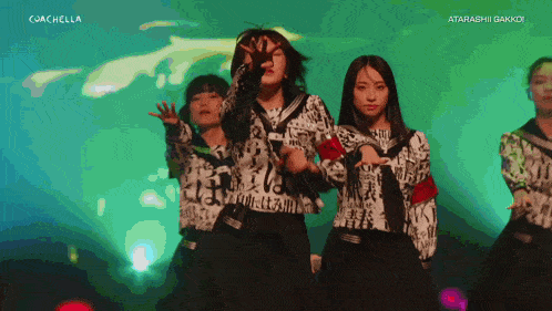 a group of girls are dancing in front of a green background that says coachella on the bottom