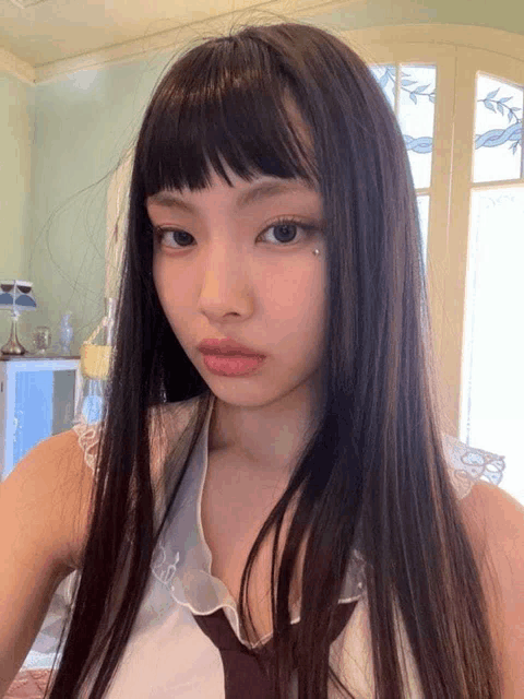 a woman with long black hair and a piercing in her eye takes a selfie