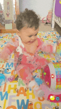 a baby is playing with a toy on a mat that has the letters j k l and m on it