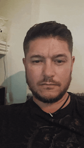 a man with a beard wears a black shirt with a skull on it
