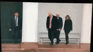 a man in a suit and tie is walking down a set of stairs with two other people .