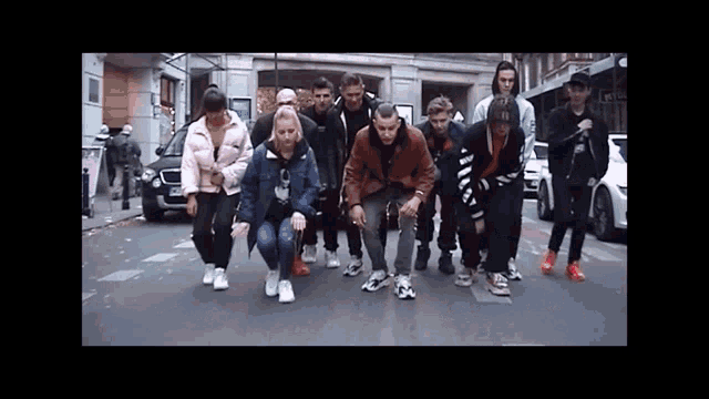 a group of people standing on a street with one wearing a jacket that says ' o ' on it
