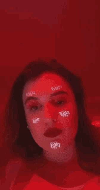 a woman with red makeup and stickers on her face is standing in front of a red wall .