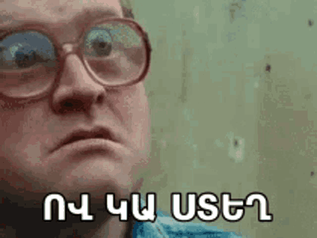 a man wearing glasses is making a funny face and has a foreign language written on his face .