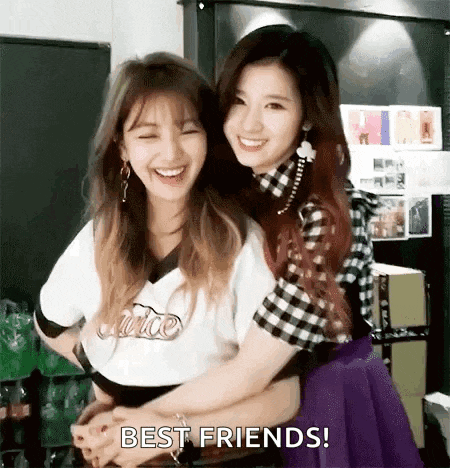 two girls are hugging each other and smiling while standing next to each other in a room .