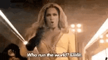 a woman in a yellow dress is holding a microphone and talking .