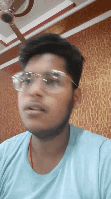 a man wearing glasses and a blue shirt is looking at the camera