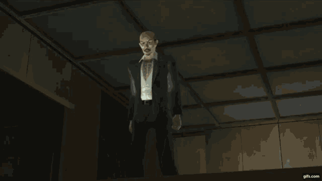 a man in a suit and white shirt is standing in a dark room with a gifs.com logo in the corner