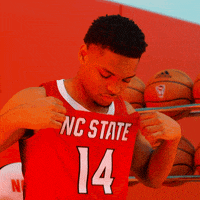 a man wearing a red nc state jersey with the number 14