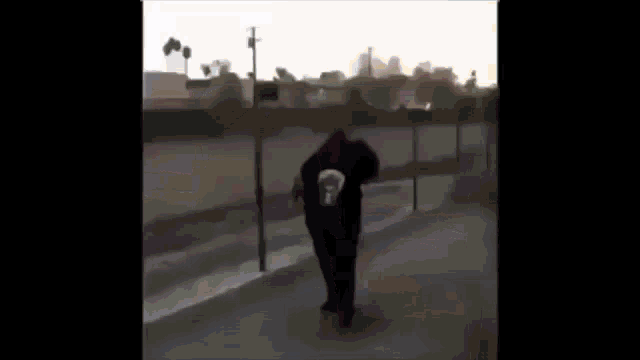 a man wearing a black hoodie with a punisher face on it is standing in the snow .