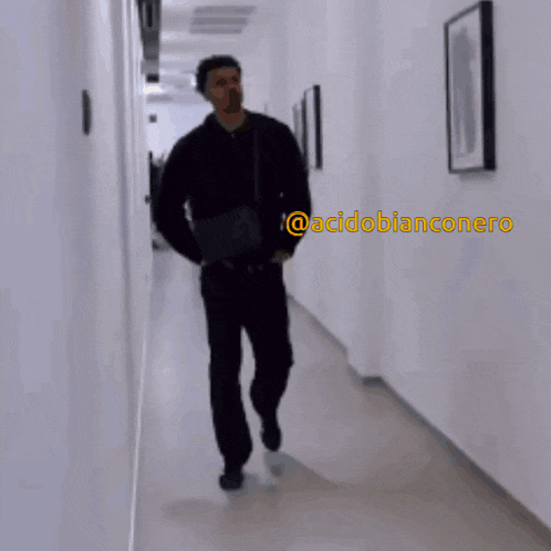 a man in a black jacket is walking down a hallway with the hashtag @acidoblanconero