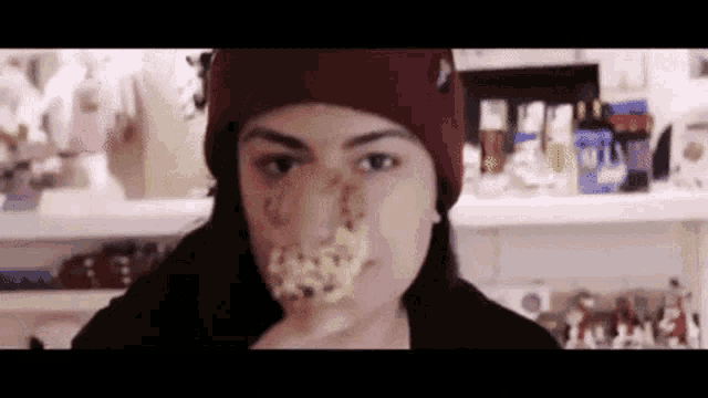 a woman wearing a red beanie is eating a cookie with a fake nose .