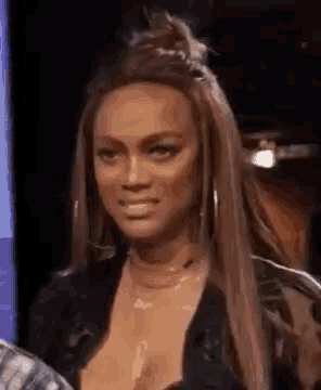 a woman with long hair is making a funny face while sitting on a stage .