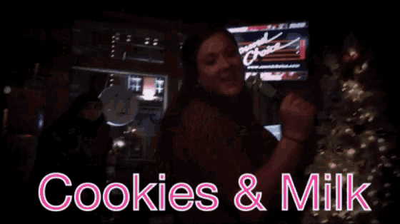 a woman singing in front of a sign that says cookies and milk