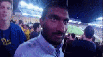 a man in a white shirt and tie is standing in a crowd of people in a stadium .